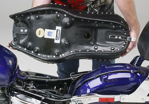 a person is holding Dual Touring seat showing rear side MPN printed and mounting brackets pre-installed