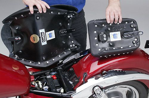 a person is holding front and rear seat showing basepan with MPN printed and mounting brackets pre-installed