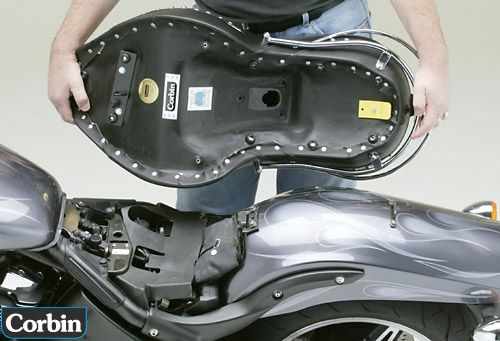 a person is holding Dual Touring seat showing basepan with MPN printed and mounting brackets pre-installed