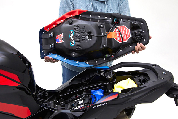 a person is holding seat showing rear side MPN printed and mounting brackets pre-installed